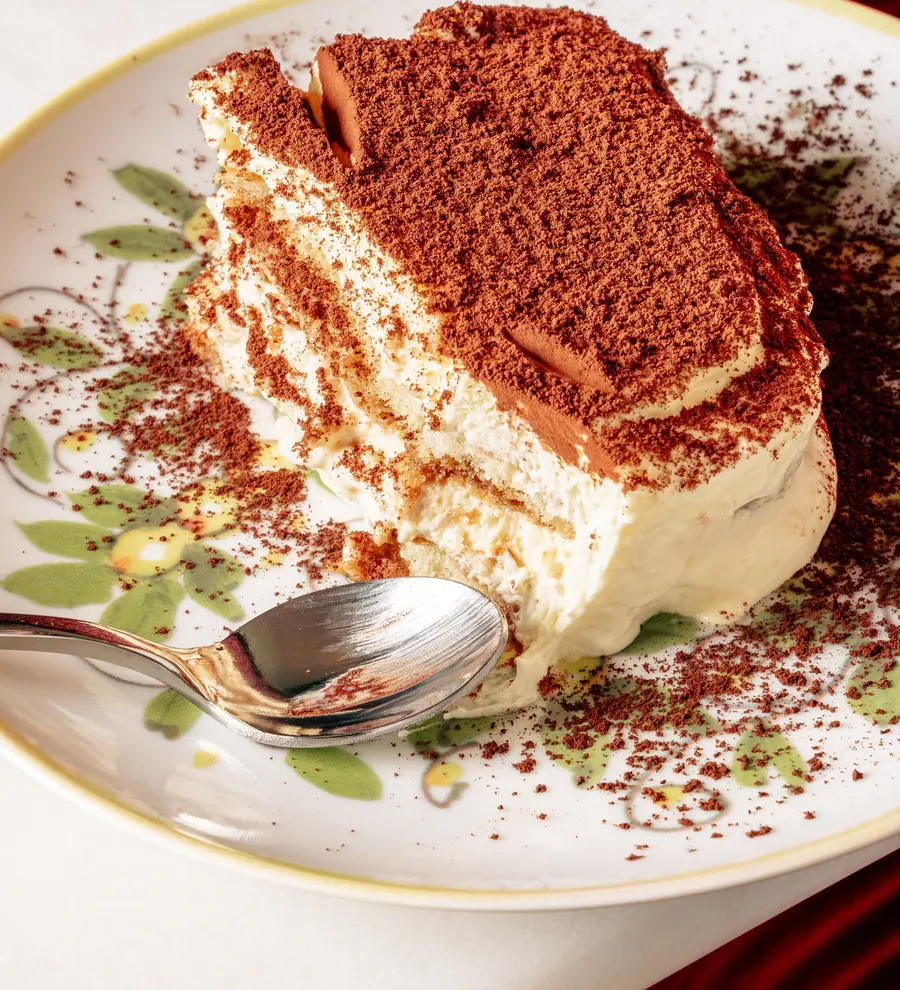 Tiramisu maison saupoudré de cacao dans une assiette en céramique italienne